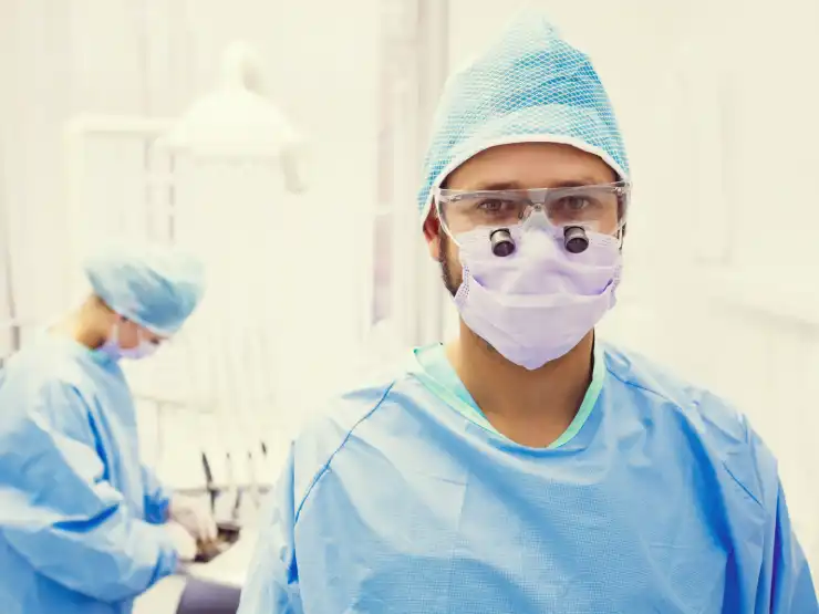 Dentist standing with dental magnification glasses and background of dental office